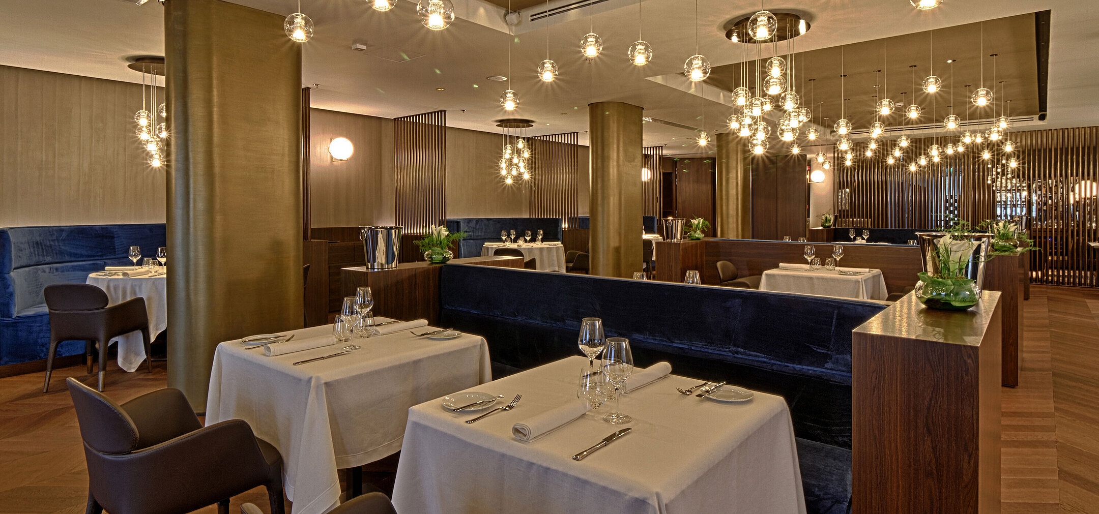 Großzügiges Restaurant mit stilvoller Beleuchtung, Holzboden und gedeckten Tischen im Maritim Hotel Plaza Tirana