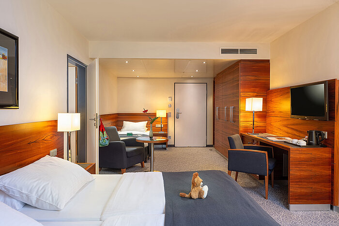 Modern eingerichtetes Familienzimmer mit Schreibtisch und gemütlicher Sitzecke im Maritim Hotel München.