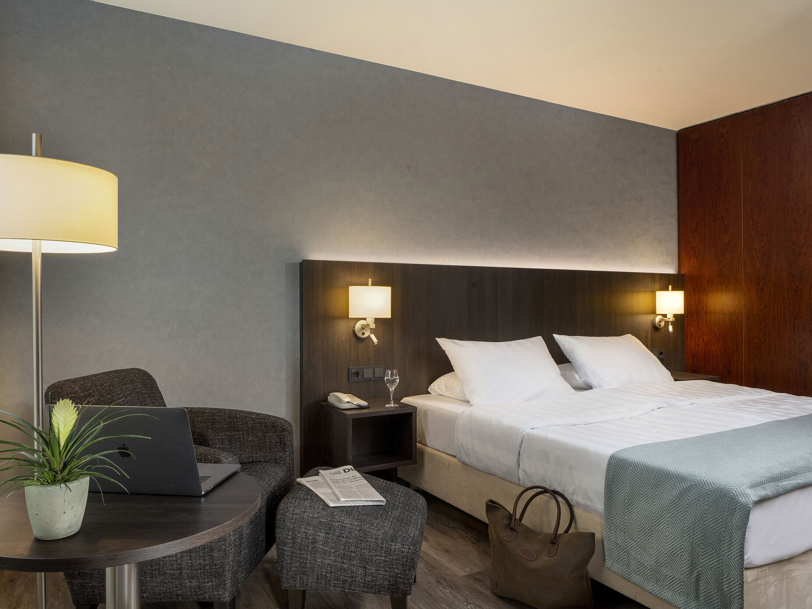 Modernes Doppelzimmer im Maritim Hotel Bremen mit gemütlicher Sitzecke, Beistelltisch, Vase und einladendem Bett.