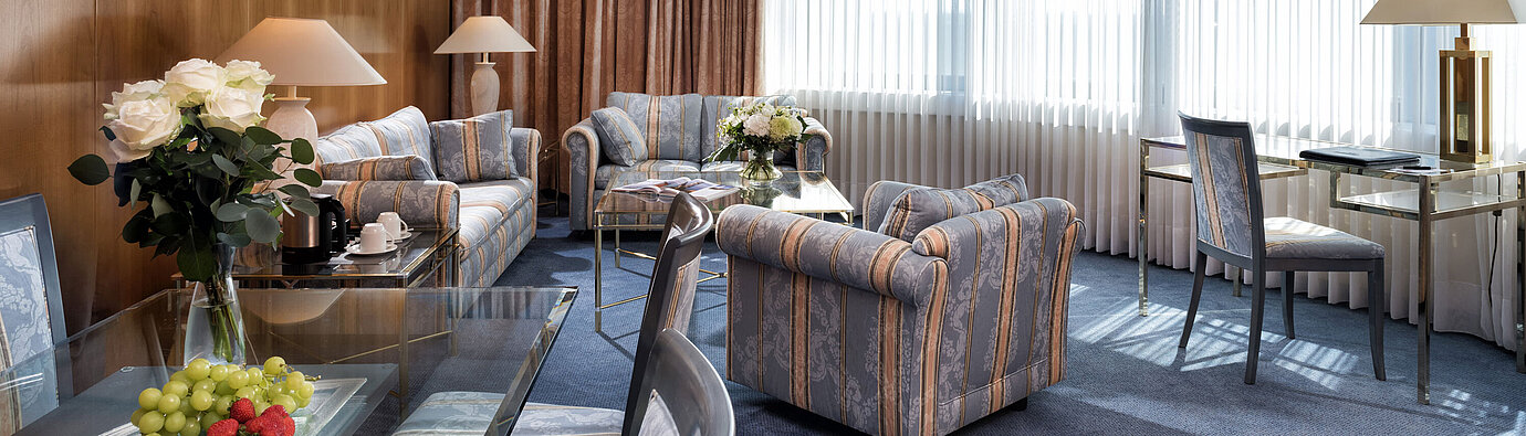 Master Suite  Elegante Master Suite im Maritim Hotel Hannover mit klassischem Design, stilvollen Sitzmöbeln und hellem Panoramafenster.