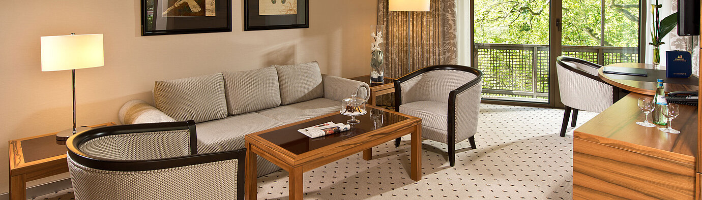 Gemütlicher Wohnbereich der Suite im Maritim Hotel Bad Homburg mit eleganter Sitzecke und Balkon.