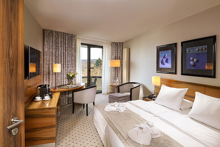 Komfortzimmer im Maritim Hotel Bad Homburg mit Balkon, hellem Design und gemütlicher Sitzecke.