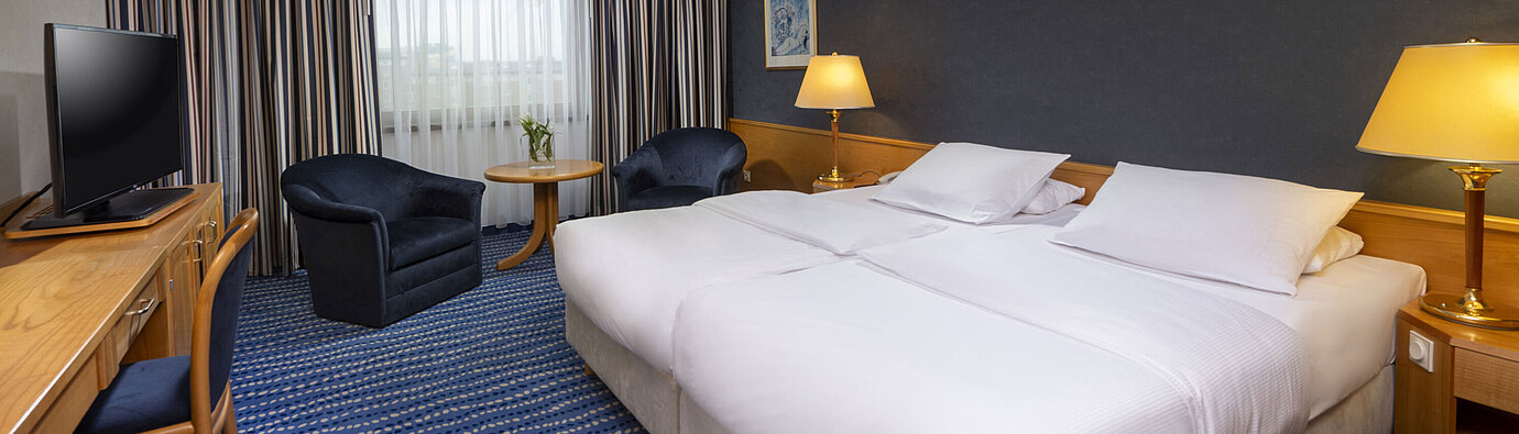 Comfort-Doppelzimmer mit Sitzbereich, Schreibtisch und modernen Kunstwerken an der Wand