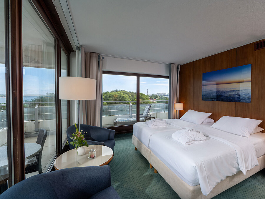 SuperiorPlus Zimmer Seeseite mit Doppelbett, Sitzecke und Blick auf die Ostsee und ins Grüne