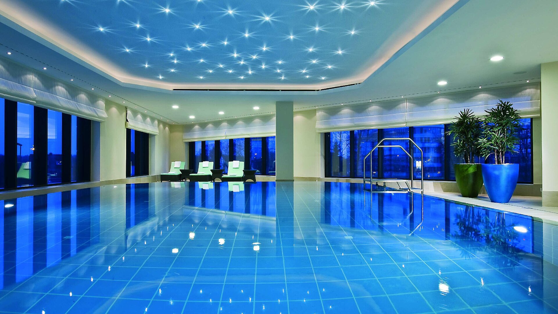 Schwimmbad Beleuchteter Innenpool im Maritim Hotel Düsseldorf mit modernen Liegestühlen und Panoramafenstern, ideal für Erholung.