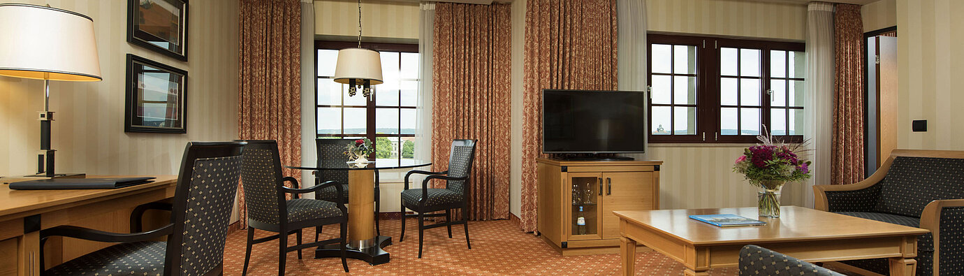 Junior Suite im Maritim Hotel Dresden mit stilvoller Sitzecke, großem Schreibtisch und moderner Einrichtung.