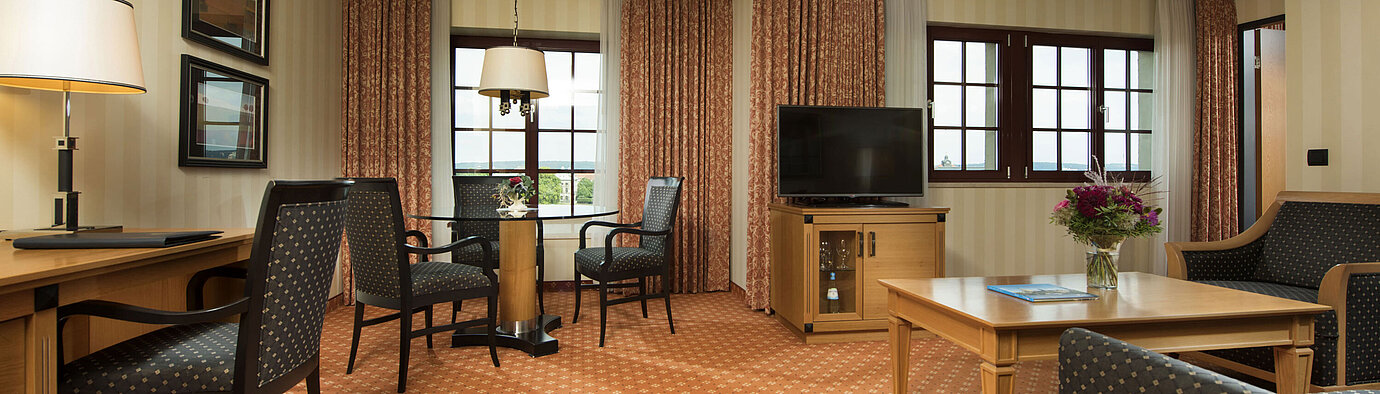 Junior Suite im Maritim Hotel Dresden mit stilvoller Sitzecke, großem Schreibtisch und moderner Einrichtung.