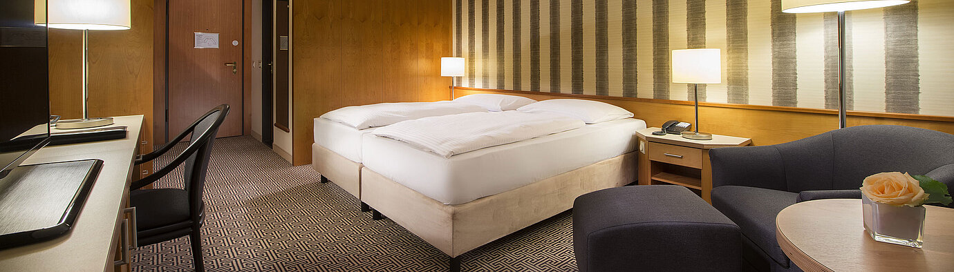 Helles Doppelzimmer mit weicher Beleuchtung und gemütlicher Sitzecke im Maritim Hotel Stuttgart
