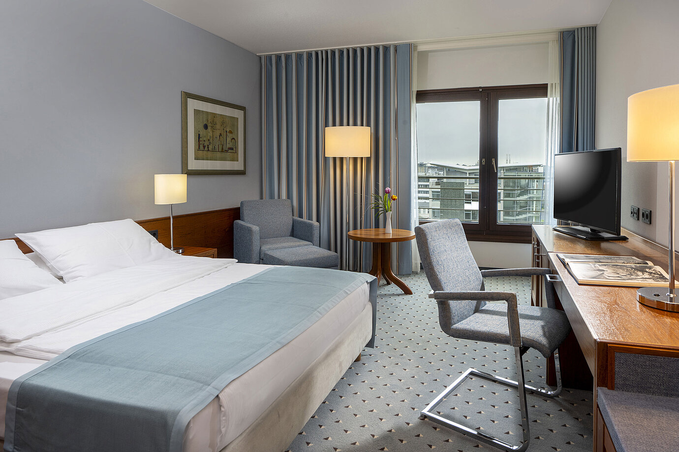 Comfort-Doppelzimmer im Maritim Hotel Darmstadt mit gemütlicher Sitzecke, modernem Schreibtisch und Blick auf die Stadt.