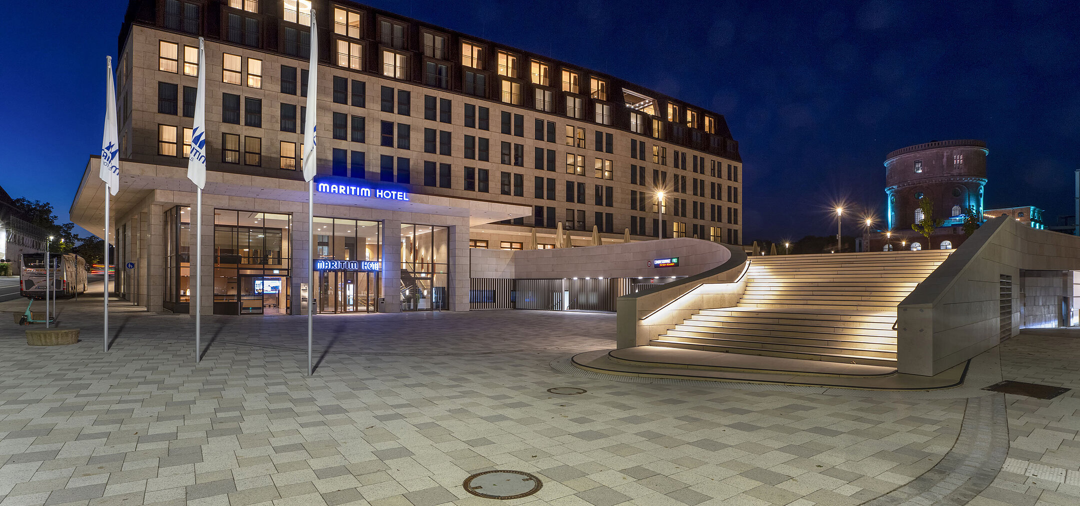 Eingangsbereich des Maritim Hotel Ingolstadt bei Nacht mit stimmungsvoller Beleuchtung und Treppe.