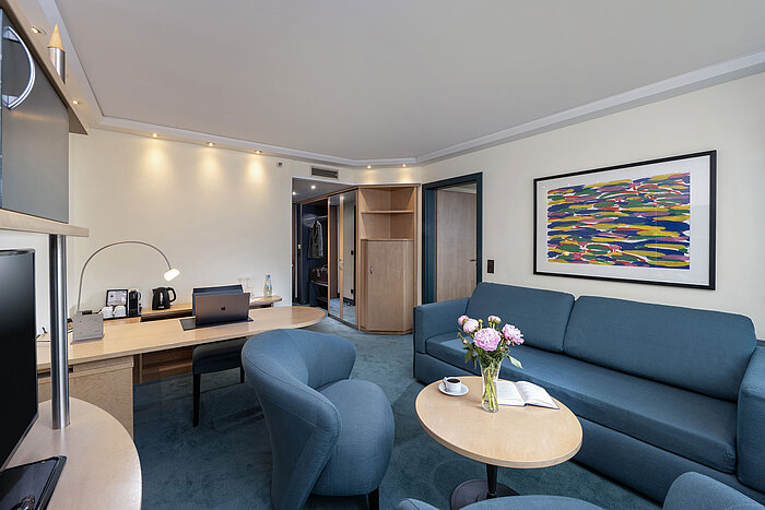 Familiensuite mit Schreibtisch, Sofa, Sesseln und Blumen im Maritim proArte Hotel Berlin