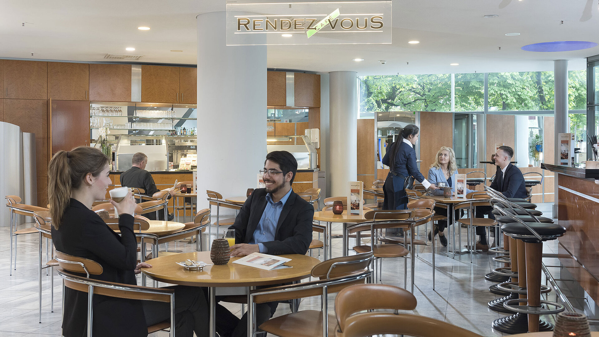 Das Café Rendezvous im Maritim Hotel Frankfurt mit Gästen, die Kaffee genießen, und freundlichem Servicepersonal.