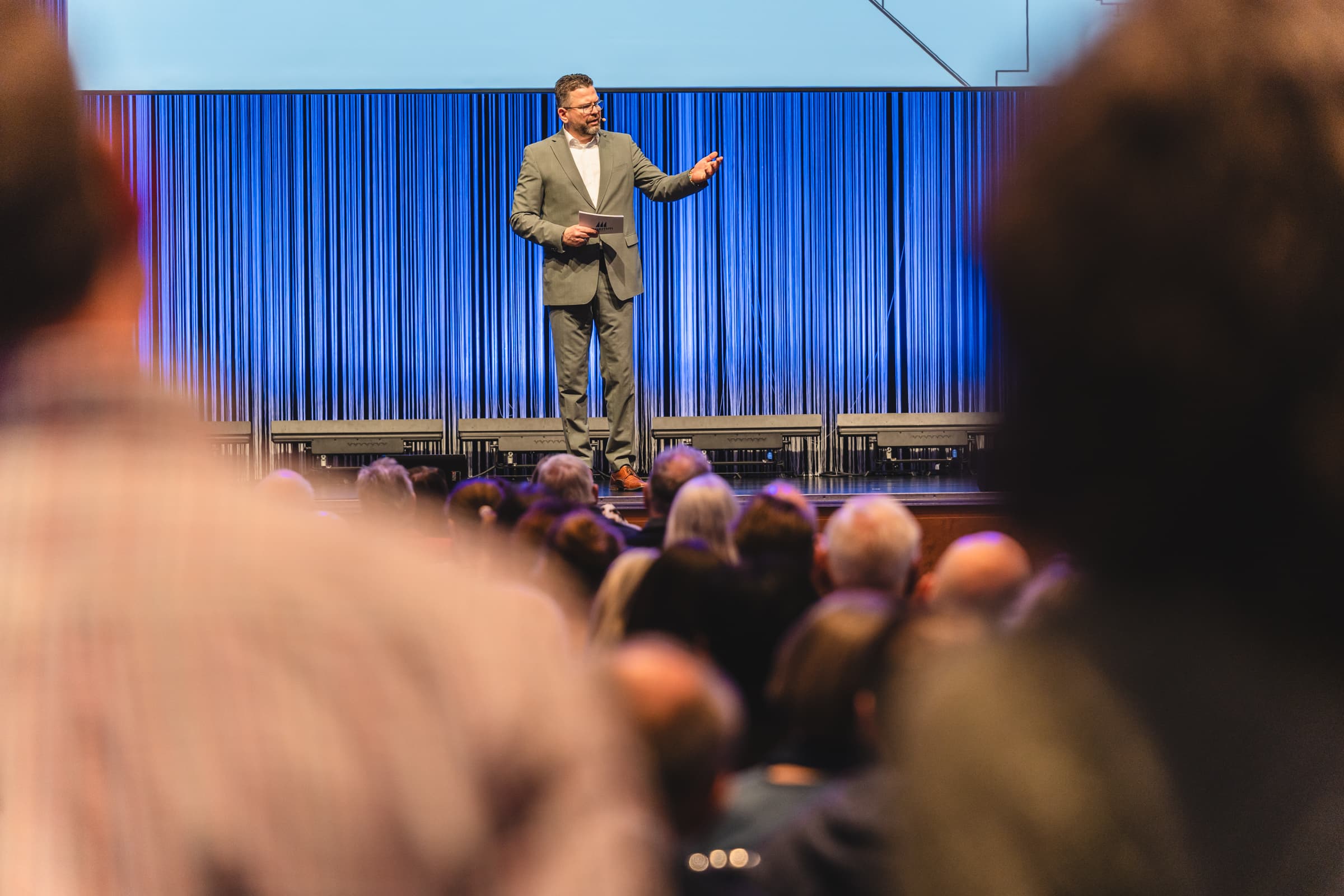 Redner auf einer Bühne vor Publikum bei einer Konferenz oder Tagung