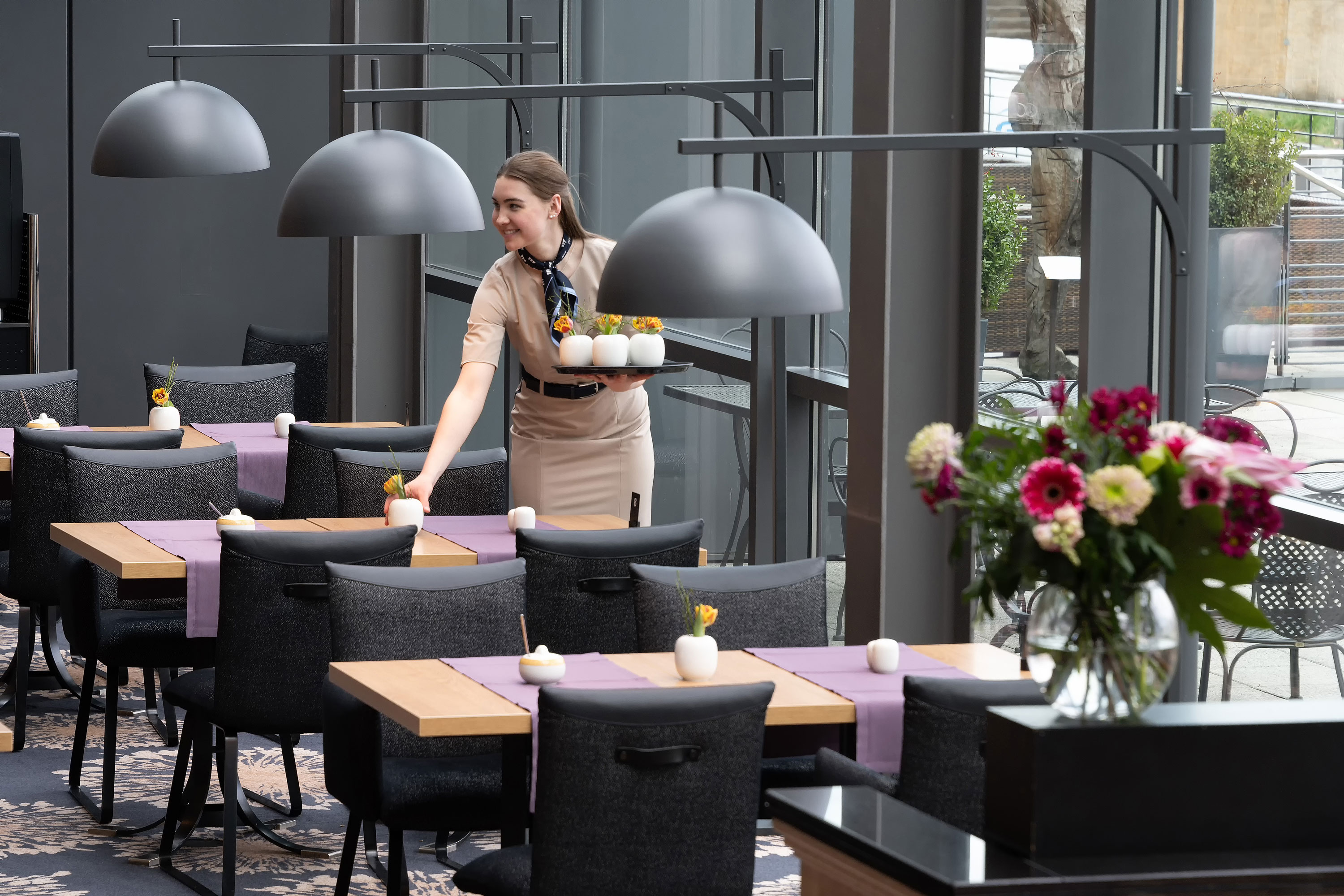 Restaurant Wintergarten Servicekraft im Restaurant Wintergarten im Maritim Hotel Dresden bereitet stilvoll gedeckte Tische vor.
