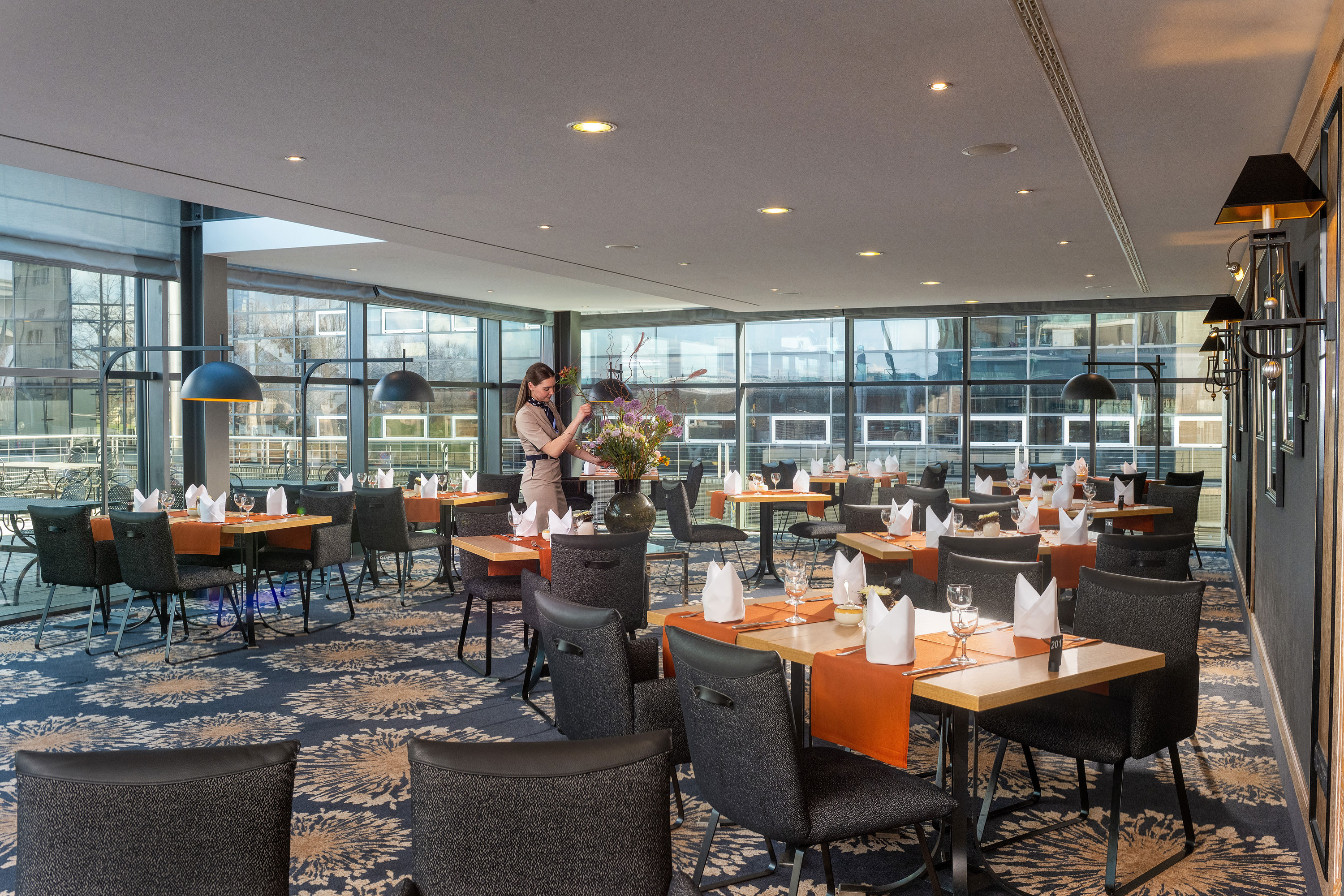 Restaurant Wintergarten Restaurant im Maritim Hotel Dresden mit Servicekraft und stilvoll gedeckten Tischen.