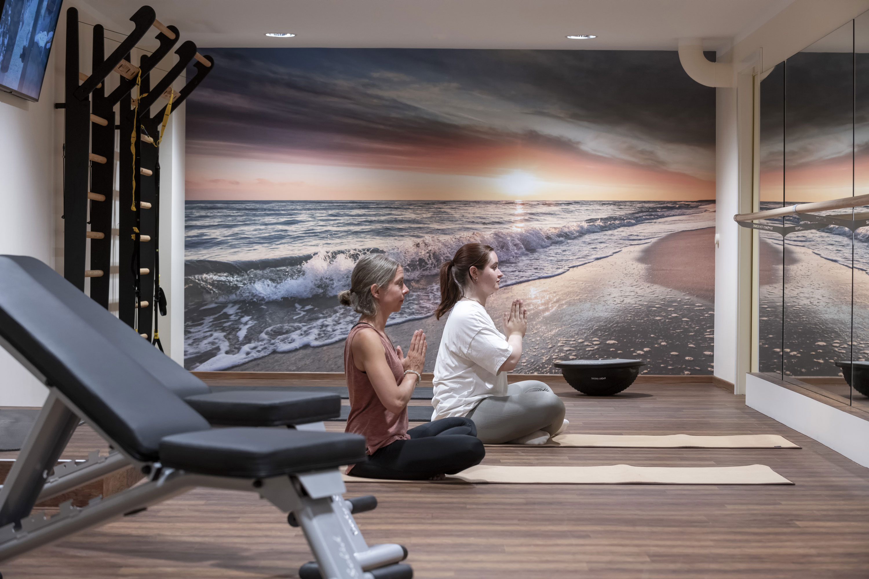 Yogastunden an der Ostsee Zwei Frauen beim Yoga im Bewegungsraum des Maritim Seehotel Timmendorfer Strand mit Strandmotiv an der Wand.