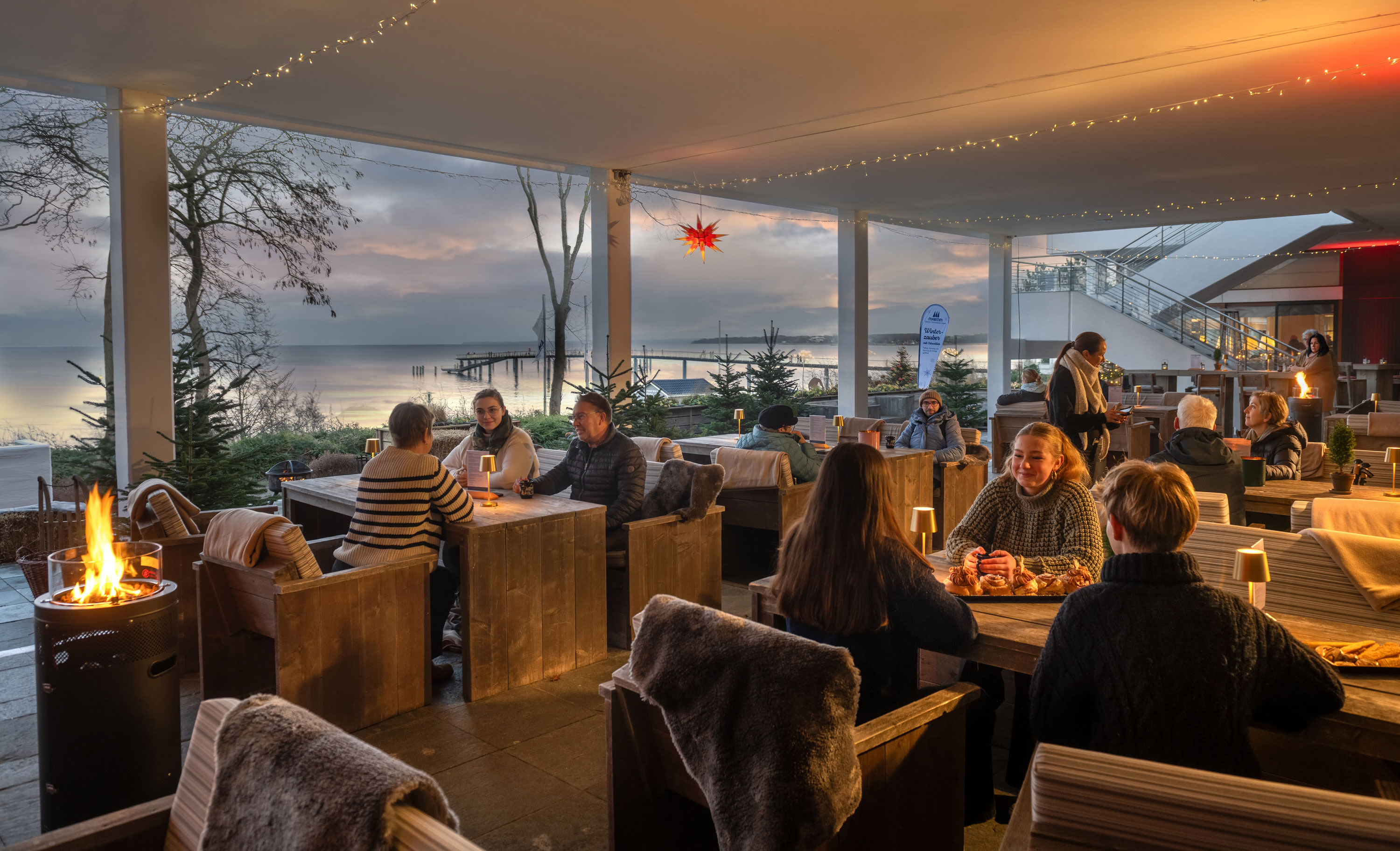 Winterliche Außenterrasse an der Ostsee für Ihr Teamevent Festlich dekorierter Terrassenbereich mit Kerzenlicht, Winterdekoration und Blick auf die Ostsee.