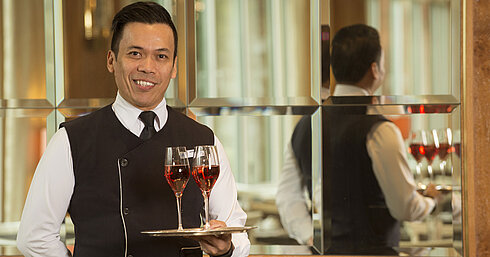 Maritim Service Kellner mit zwei Gläsern Roséwein auf Silbertablett im Maritim Hotel Stuttgart, freundlich und professionell